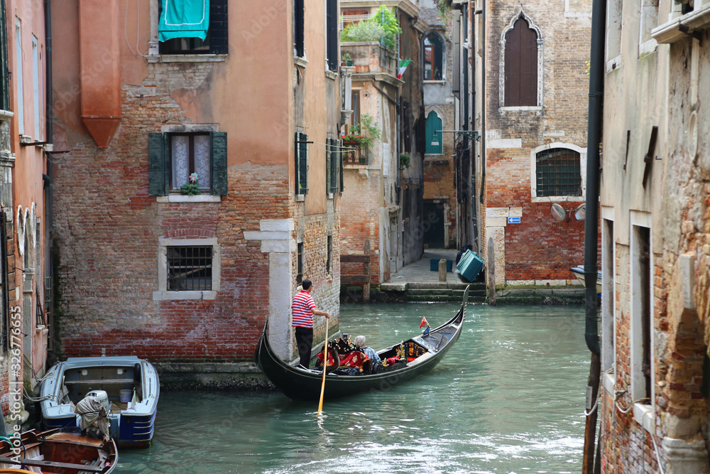 A canal in Venice, Italy with a gondolier and boat A canal in Venice, Italy with a gondolier and boat