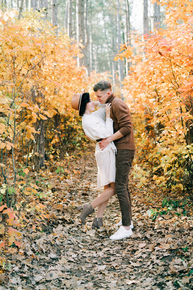 two happy lovers embrace each other in the middle of a pine forest in the autumn, around the Golden leaves on the trees two happy lovers embrace each other in the middle of a pine forest in the autumn, around the Golden leaves on the trees