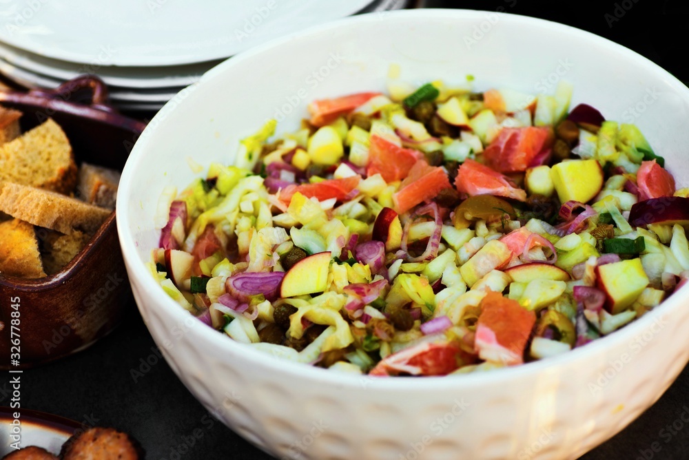 Chicory, apples, oranges, onion and capers salad in bowl, croutons and plates. Chicory, apples, oranges, onion and capers salad in bowl, croutons and plates.