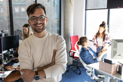 Portrait of senior programmer and group leader.he standing at the office in front of his workers.