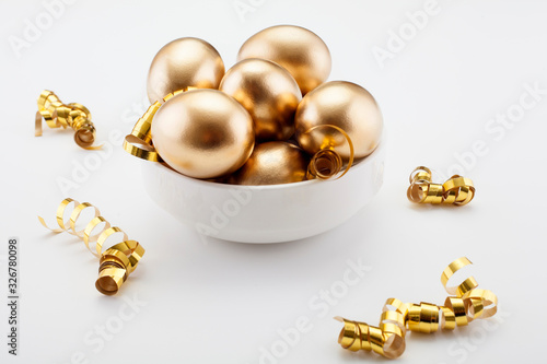 Golden eggs on a white background, decorated with gold ribbons. The concept of Passover and the holiday symbol.