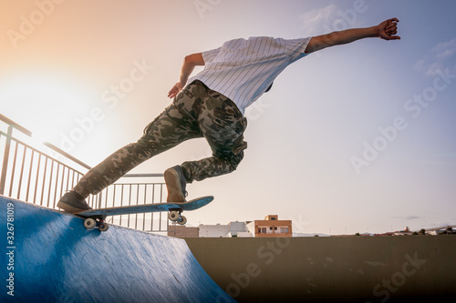 joven skater toca el borde de la rampa con su tabla al atardecer