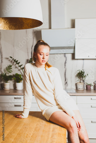 Thoughtful woman sitting on wooden kitchen table