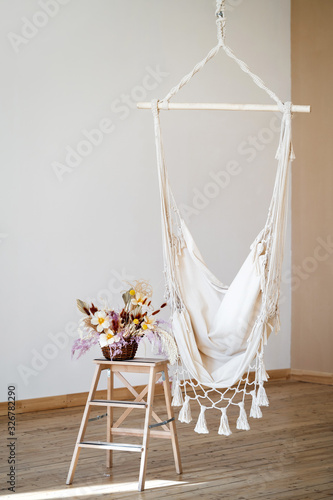 Fototapeta Naklejka Na Ścianę i Meble -  cozy hammock in the interior in the loft style and a flower arrangement on a wooden ladder.