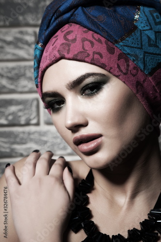 Portrait of a beautiful sexy brunette girl with bright makeup and oriental turban