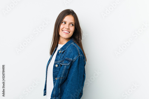 Young cute woman looks aside smiling, cheerful and pleasant.