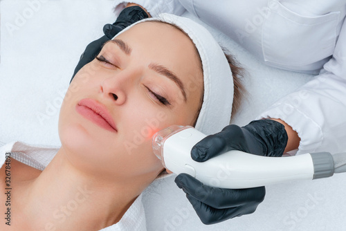 Young woman receiving laser treatment in cosmetology clinic Poster Mural XXL