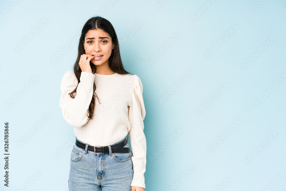 Young indian woman isolated on blue background biting fingernails, nervous and very anxious. Young indian woman isolated on blue background biting fingernails, nervous and very anxious.