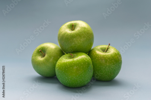 A bunch of beautiful green apples on an isolated blue background. Top view with copy space