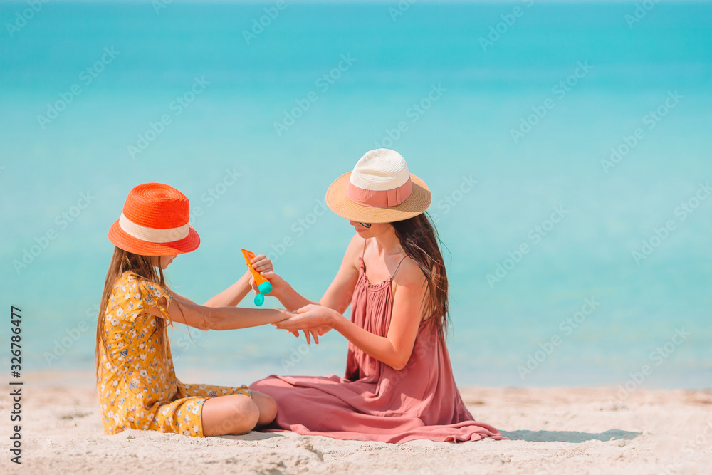 Young mother applying sun cream to daughter nose on the beach. Sun protection