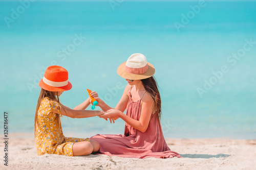 Obraz na płótnie Young mother applying sun cream to daughter nose on the beach. Sun protection w salonie