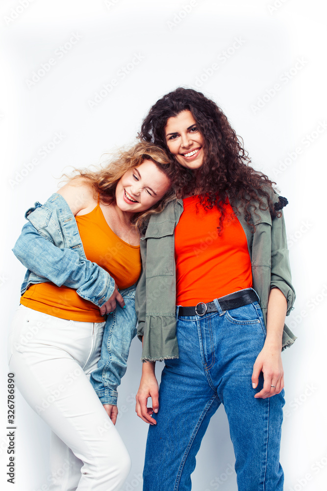 young pretty teenage girls friends with blond and brunette curly hairs posing cheerful isolated on white background, lifestyle people concept young pretty teenage girls friends with blond and brunette curly hairs posing cheerful isolated on white background, lifestyle people concept