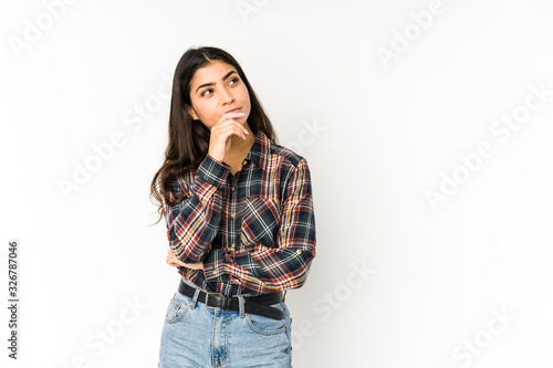 Young indian woman isolated on purple background relaxed thinking about something looking at a copy space.