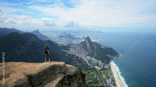 Happy traveler on the top of Pedra da Gavea mountain with panoramic aerial view to the Rio de Janeiro landscape in Brazil.