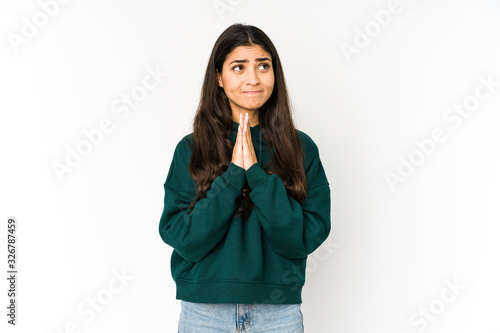 Young indian woman isolated on purple background holding hands in pray near mouth, feels confident. © Asier