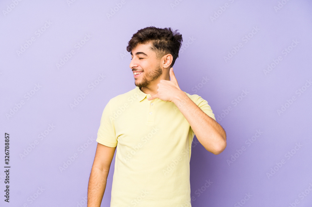 Young arabian man isolated on a purple background showing a mobile phone call gesture with fingers. Young arabian man isolated on a purple background showing a mobile phone call gesture with fingers.