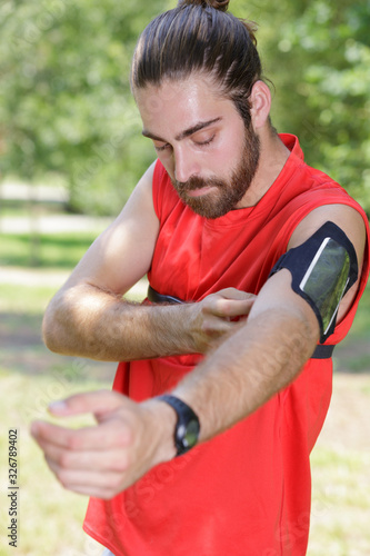 handsome jogger adjusting his music device