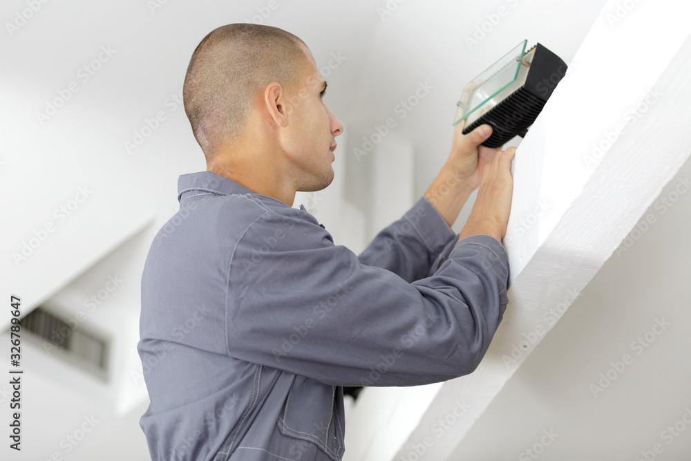 young electrician installing ceiling light young electrician installing ceiling light