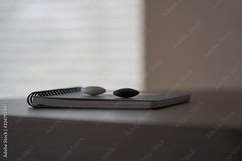 Couple of go game stones on the surface of notepad with blurred background Couple of go game stones on the surface of notepad with blurred background