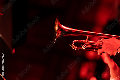 A trumpet player playing the trumpet in a big band concert on stage with red stage lights