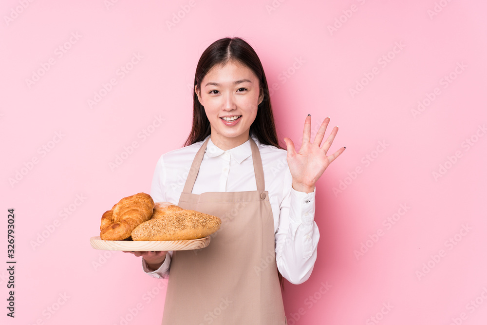 Young chinese baker woman isolated smiling cheerful showing number five with fingers. Young chinese baker woman isolated smiling cheerful showing number five with fingers.