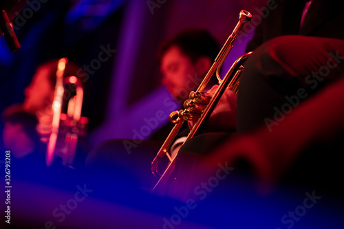 Canvas Print A trumpet player dressed in concert black sitting and holding a gold plated trumpet