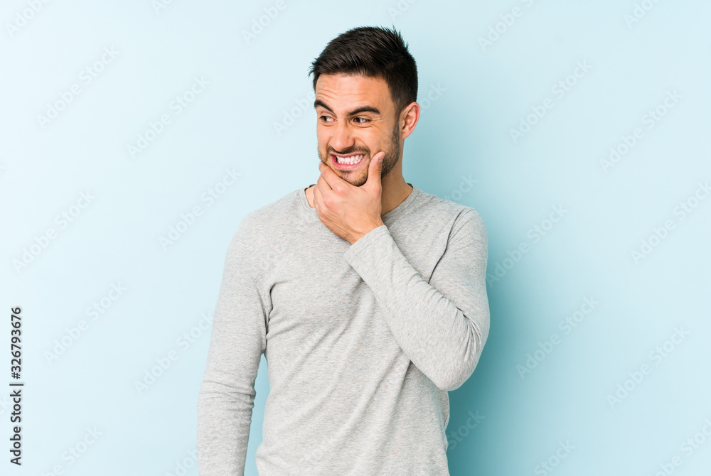 Young caucasian man isolated on blue background touching back of head, thinking and making a choice. Young caucasian man isolated on blue background touching back of head, thinking and making a choice.