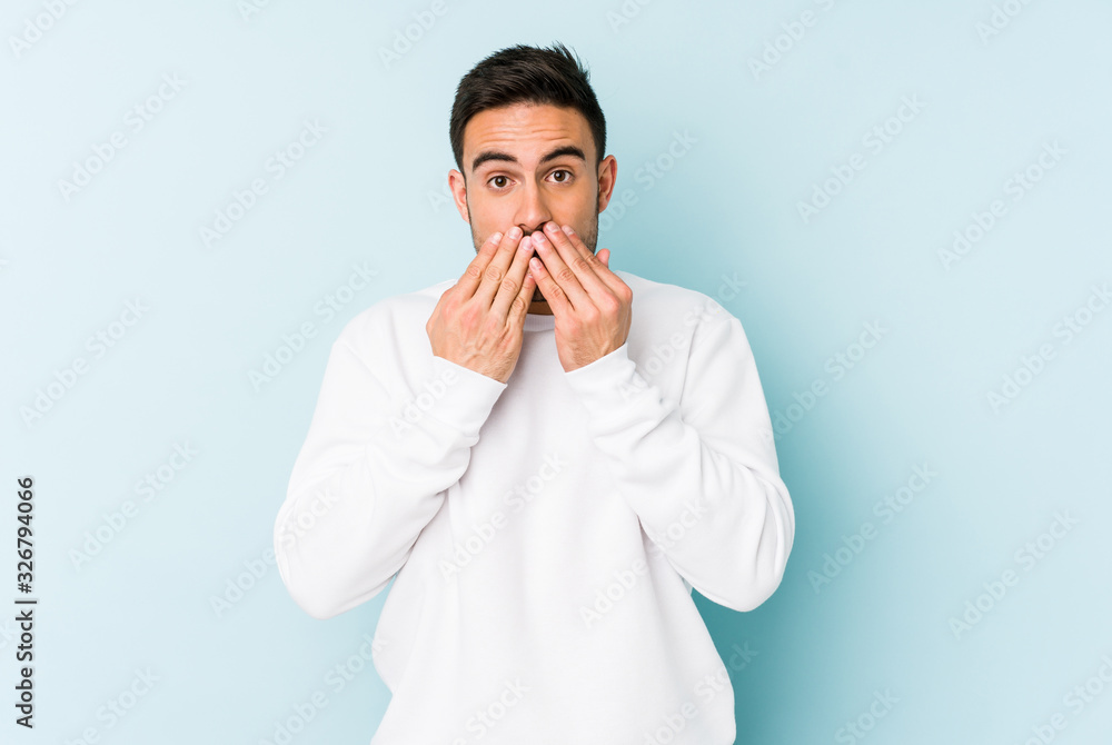 Young caucasian man isolated on blue background shocked covering mouth with hands. Young caucasian man isolated on blue background shocked covering mouth with hands.