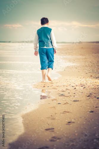 The young Caucasian walks barefoot on the beach near the sea, footprints in the sand © Juan Manuel Pichardo