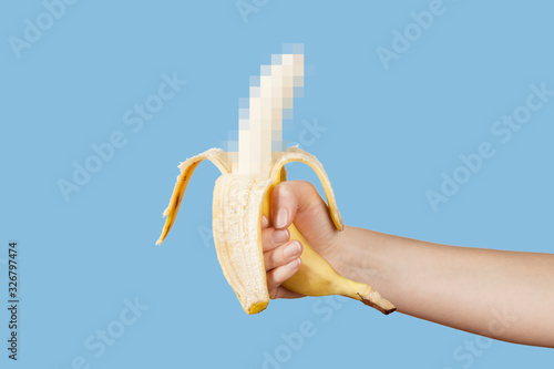 Print op canvas Hidden censored banana in hand on a blue background