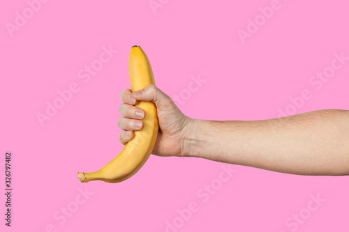 Banana as a symbol of male penis in hand on a yellow background hidden by censorship. Sexual masturbation and orgasm, impotence problem. Self-pleasure concept. photo