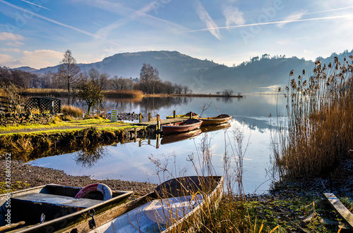 Boats at rest on Grasmere water by the village in the centre of the Lake District Cumbria. .  photo