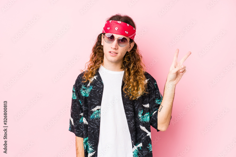 Young hippie caucasian man isolated joyful and carefree showing a peace symbol with fingers.