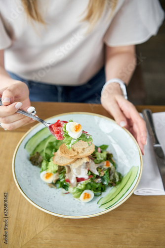 Wallpaper Mural Woman eats Olivier salad with Lamb tongue, salted cucumber, quail egg. Wooden table background. Menu restaurant. Russian traditional salad Torontodigital.ca