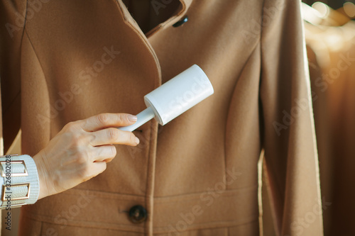 Closeup on woman cleaning coat with lint roller photo