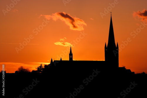 Church building exterior in silhouette of sunrise or sunset with glowing sunlight