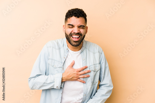 Young mixed race arabic man isolated laughs happily and has fun keeping hands on stomach.