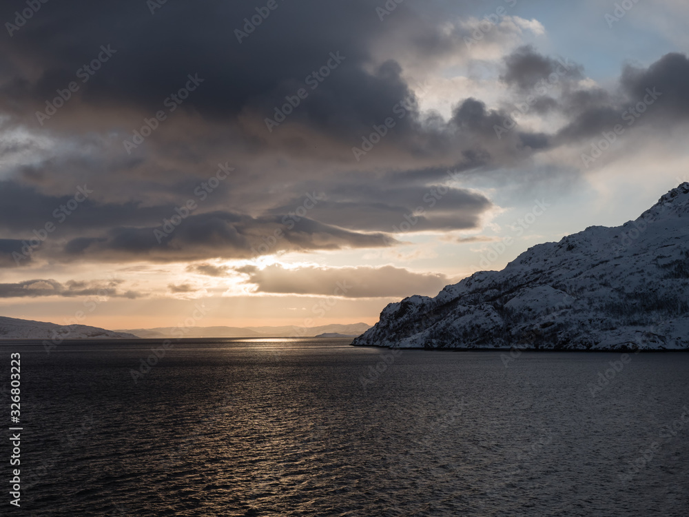 Sonnenaufgang Altafjord mit schneebedeckten Bergen und dramatischen Wolken