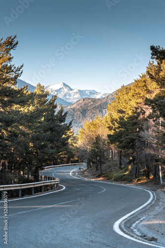 Mountain road with curves and snowy mountain in the background. Travel concept