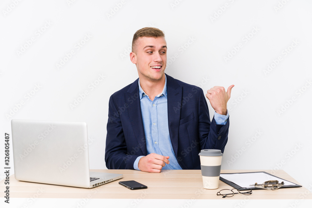 Young business man with a laptop points with thumb finger away, laughing and carefree. Young business man with a laptop points with thumb finger away, laughing and carefree.