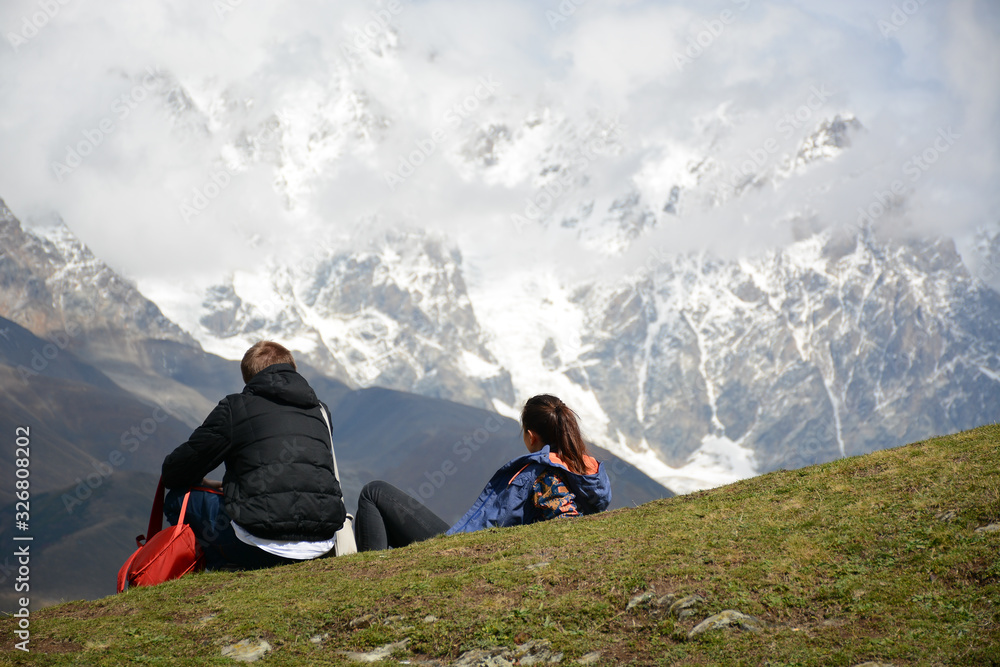 Fototapeta premium Ushguli, Georgia - October 3, 2018: Couple of tourists is looking to the mountains in village of Ushguli in Svaneti region