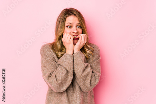 Young caucasian woman isolated on pink background biting fingernails  nervous and very anxious.