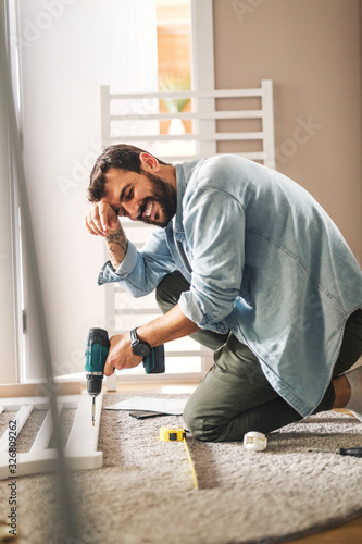 Man looking tired while screwing baby crib.