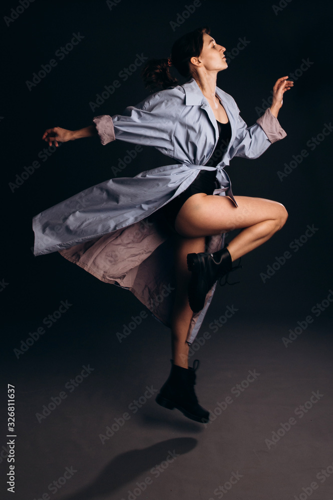 A girl in a blue cloak and with slim legs is jumping dynamically. The girls legs are black boots.