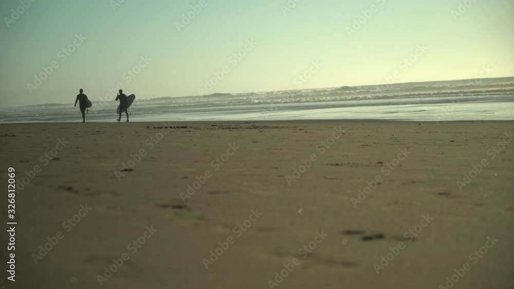 Two surfers walking along beach Two surfers walking along beach