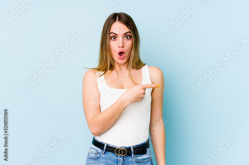 Young caucasian woman isolated on blue background pointing to the side © Asier