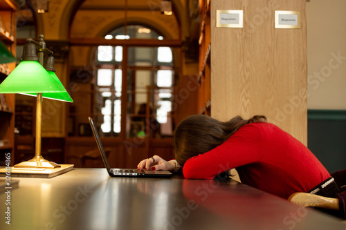 Sleeping young Woman Student Sitting And Leaning On a laptop at the library