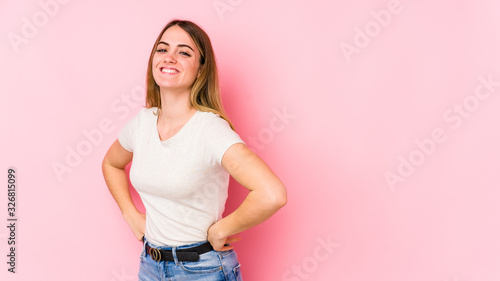 Young caucasian woman isolated on pink background laughs happily and has fun keeping hands on stomach. © Asier