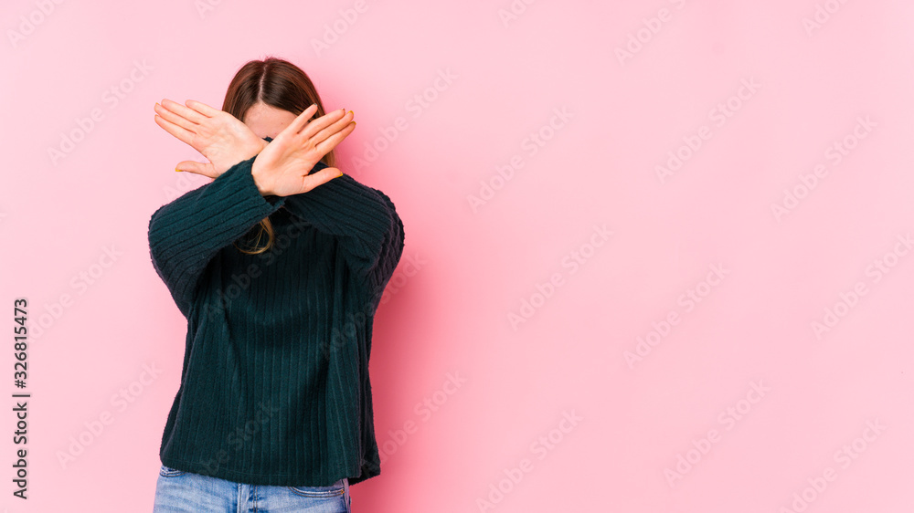 Fototapeta premium Young caucasian woman isolated on pink background keeping two arms crossed, denial concept.