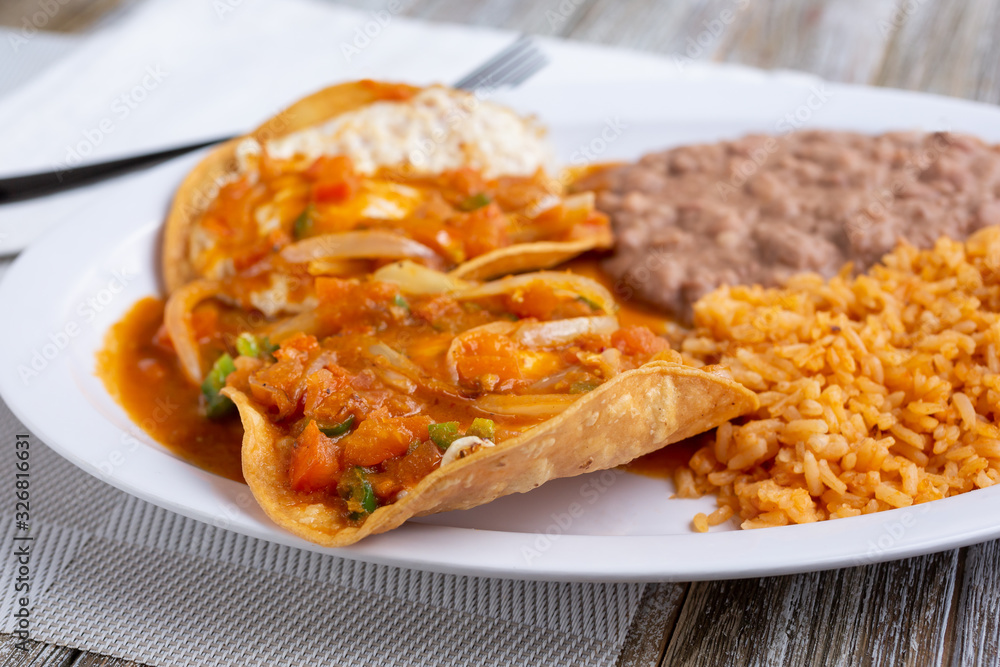 A view of a plate of huevos rancheros, in a restaurant or kitchen setting. A view of a plate of huevos rancheros, in a restaurant or kitchen setting.